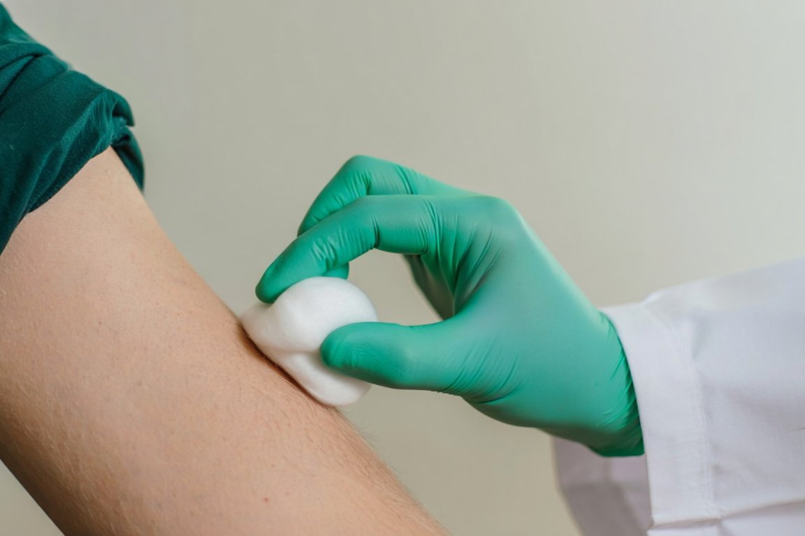 Врач обрабатывает область для укола ватным диском